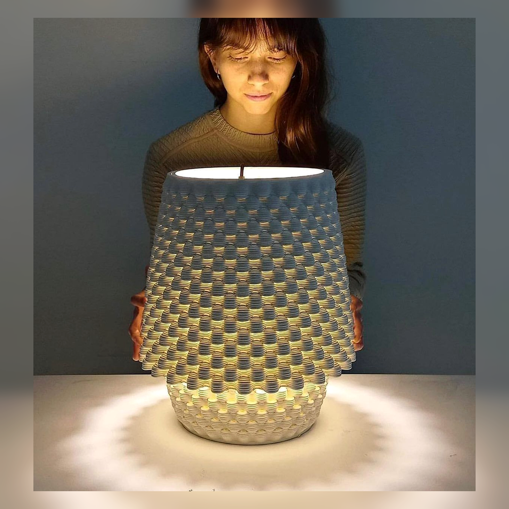 Person holding a textured glowing ceramic table lamp.