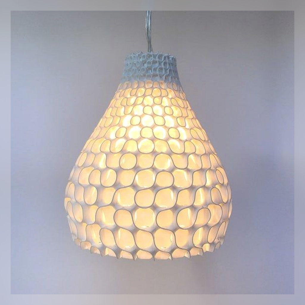 Lit detail of a ceramic pendant shade with organic openings.